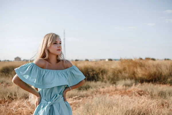 Junge schöne kaukasische blonde Mädchen in hellblauem Kleid steht — Stockfoto