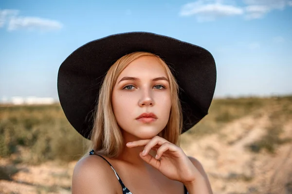 Un retrato de cerca de una rubia de ojos azules con un sombrero negro y — Foto de Stock