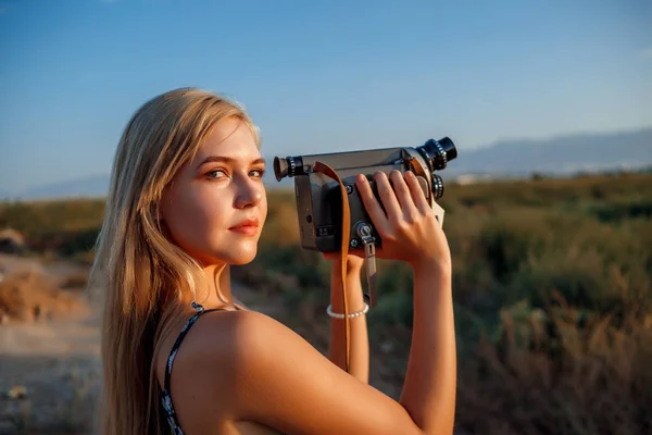 รูปภาพของสาวผมบลอนด์ในชุดพิมพ์ดอกไม้กับวิดีโอวินเทจ — ภาพถ่ายสต็อก