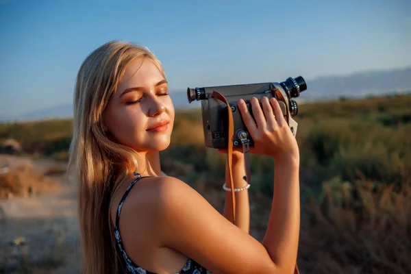 รูปภาพของสาวผมบลอนด์ในชุดพิมพ์ดอกไม้กับวิดีโอวินเทจ — ภาพถ่ายสต็อก