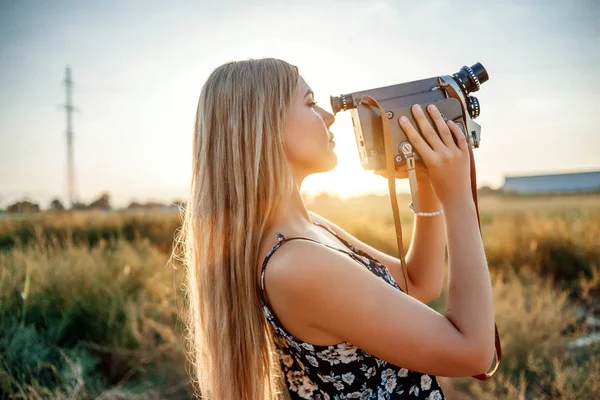 รูปภาพของสาวผมบลอนด์ในชุดพิมพ์ดอกไม้กับวิดีโอวินเทจ — ภาพถ่ายสต็อก