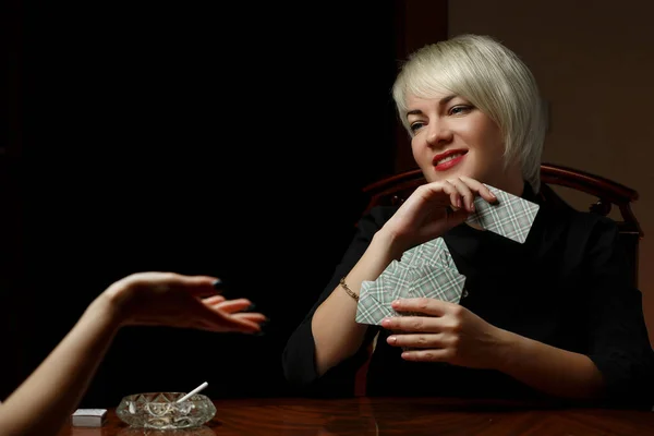 Молодая кавказская блондинка в черной одежде сидит за столом — стоковое фото