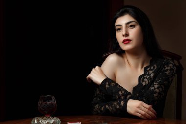 Siyah elbiseli, kızıl dudaklı, güzel esmer bir kadın.