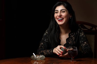 Siyah elbiseli, kızıl dudaklı, güzel esmer bir kadın.