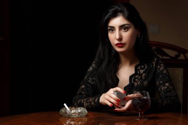 Siyah elbiseli, kızıl dudaklı, güzel esmer bir kadın.