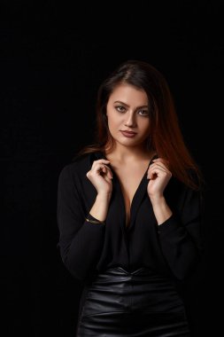 Siyah düğmesiz gömlekli güzel siyah saçlı bir kadın göğüslerini ve siyah deri bir eteğini ortaya çıkardı..