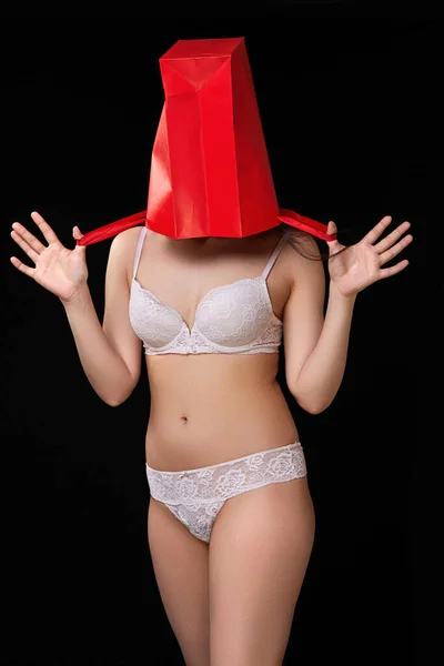 一个穿着白内裤 头上顶着红纸购物袋 背景为黑色孤立背景的年轻漂亮女人 — 图库照片