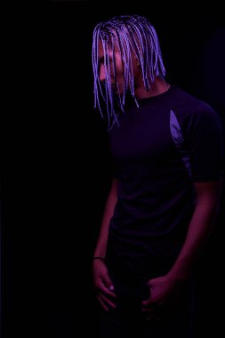 Stüdyoda çıplak bir Afrikalı adamın portresi. Renkli parlak ışıklarla siyah arka planda poz veren yüksek moda erkek model. Sanat tasarımı konsepti. seçici odak.