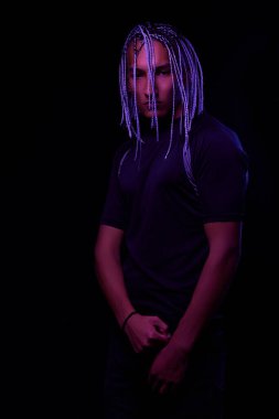 Stüdyoda çıplak bir Afrikalı adamın portresi. Renkli parlak ışıklarla siyah arka planda poz veren yüksek moda erkek model. Sanat tasarımı konsepti. seçici odak.