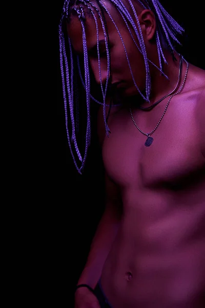 portrait of a young naked african man at studio. High Fashion male model in colorful neon bright lights posing on black background. Art design concept. selective focus.