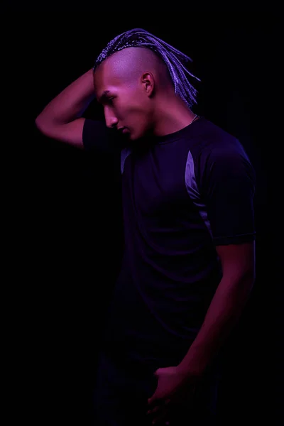 portrait of a young naked african man at studio. High Fashion male model in colorful neon bright lights posing on black background. Art design concept. selective focus.