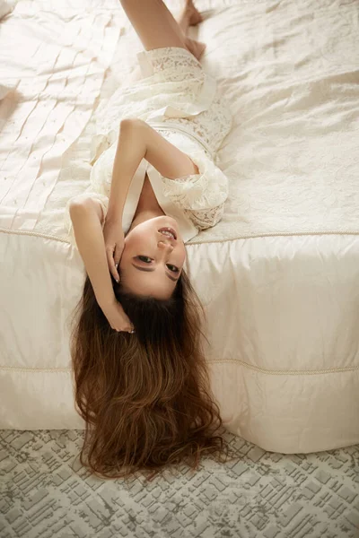 ベージュのレースのナイトガウンを着た若い美少女がベッドの上で横になっている — ストック写真