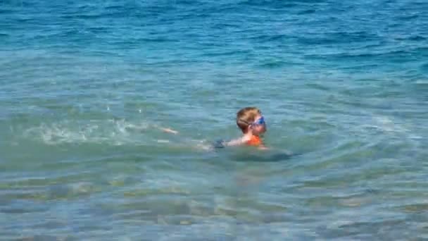 Un niño pequeño aprende a nadar en el mar abierto, en la naturaleza . — Vídeo de stock