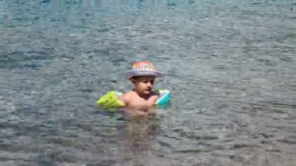 Un niño pequeño aprende a nadar en el mar abierto, en la naturaleza — Vídeos de Stock