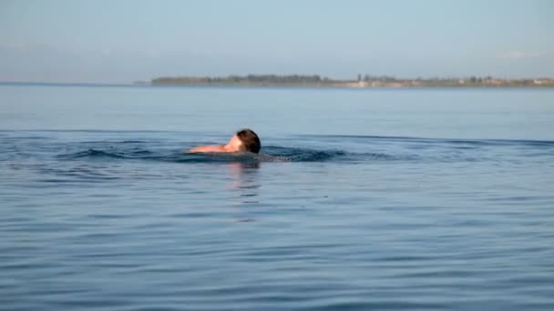 Um homem nada no lago no início da manhã — Vídeo de Stock