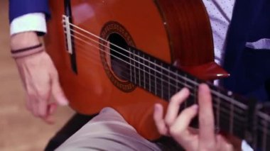 Klasik İspanyol akustik gitar çalan müzisyen ellerinin yakın çekim. Bir elden diğerine hareket eden odak.