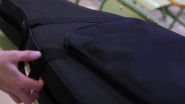 Siyah bir kılıf açan ve klasik İspanyol akustik gitarı alan müzisyenin yakın çekim.