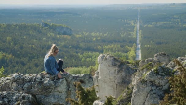 Kvinnan sitter på toppen av en klippig kulle Videoklipp
