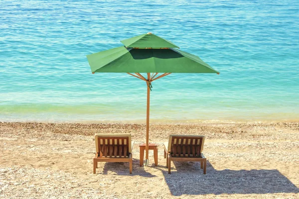 Güneşlenme ve güneşli bir deniz arka plan üzerinde şemsiye
