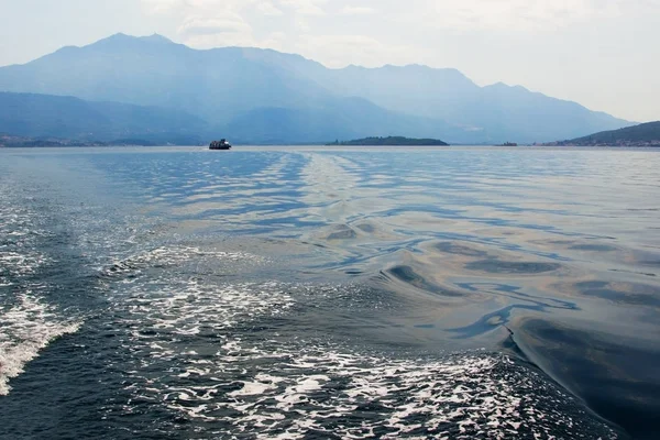 Deniz ve dağlar akşam ışığında. Ufukta yalnız bir gemi