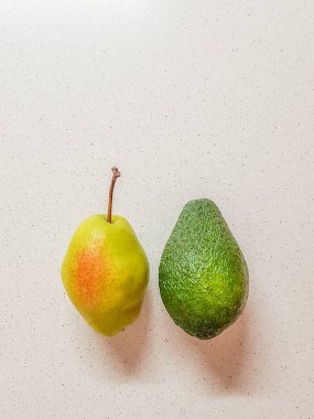 Olgun sarı armut ve avokado beyaz mermer masada. Üstten görünüm