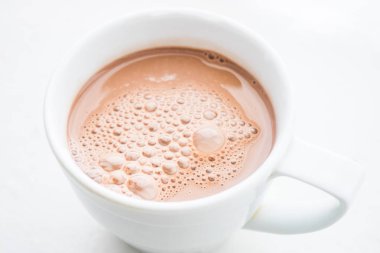 Kakao içmek kabarcıklar masanın üzerinde beyaz bir kupa ile. Yukarıdan görüntülemek.