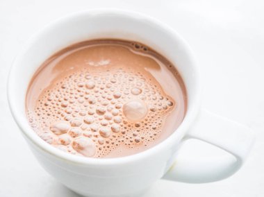 Kakao içmek kabarcıklar masanın üzerinde beyaz bir kupa ile. Yukarıdan görüntülemek.