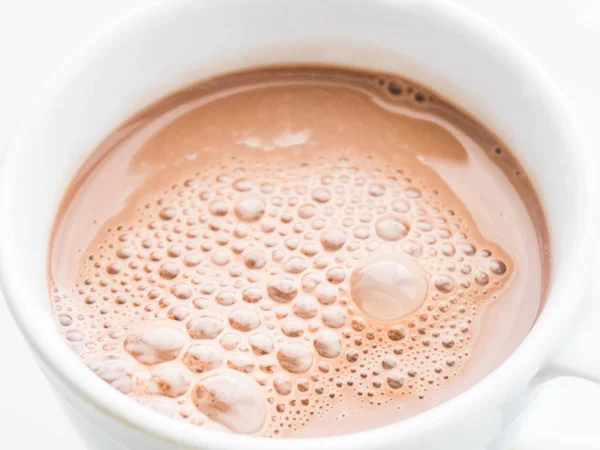 Cocoa drink with bubbles in a white mug close-up