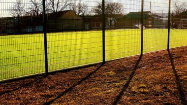 Çit örgüsünün arkasında minifootbol oynamak için çim sahası