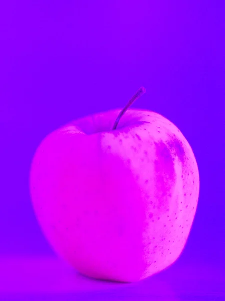 Masanın üzerinde bir elma. Neon ışık.