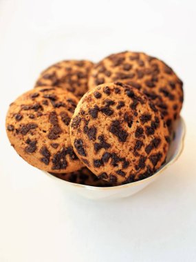 Yulaf ezmeli kurabiye, çikolatalı dilimleri ile serpilir. Şekerli tatlı beyaz bir tablo üzerinde küçük bir daire içinde. Beyaz arka plan