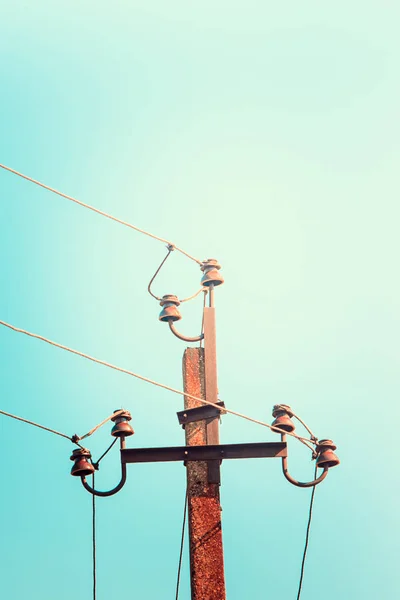 top old electrical pillar on a background of the blue sky.