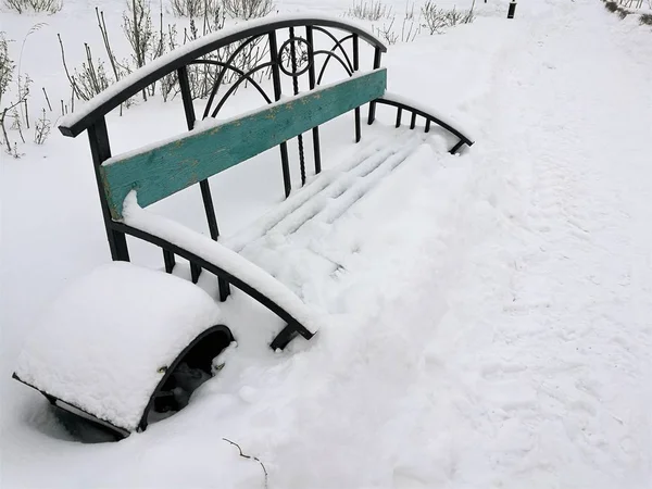 Winter park with snow covered bench under snow