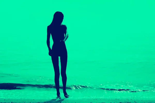 Silhouette eines schlanken jungen Mädchens, das am Strand entlang läuft — Stockfoto