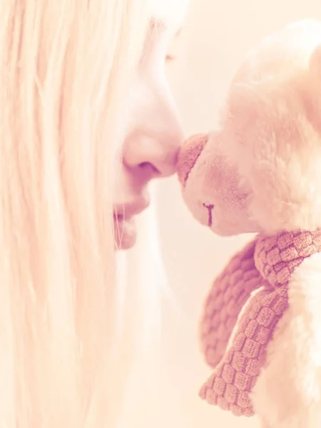 portrait of a girl with a soft toy bear nose to nose