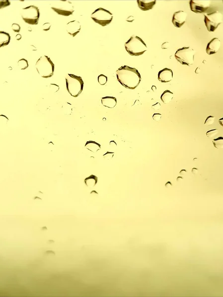 Gocce d'acqua sul vetro giallo pallido . — Foto Stock