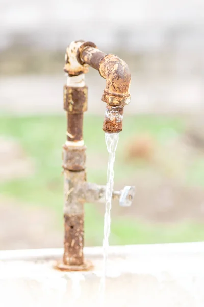 Vieux robinet d'eau rouillé avec de l'eau courante dans le jardin . — Photo