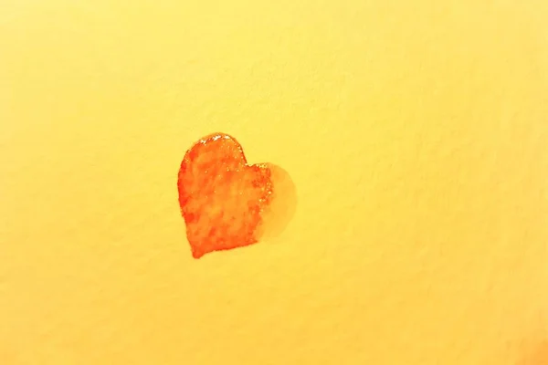 Corazón rojo pequeño y húmedo pintado sobre papel amarillo . —  Fotos de Stock