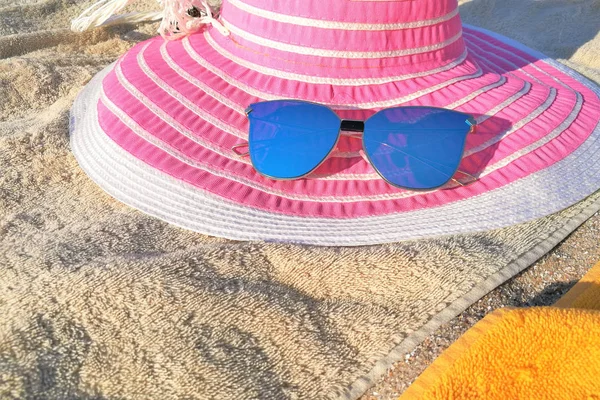 Рожевий жіночий капелюх і блакитні сонцезахисні окуляри на пляжі — стокове фото