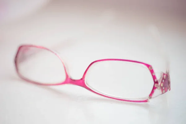 Old glasses with violet rim lie on a white table — Stock Photo, Image