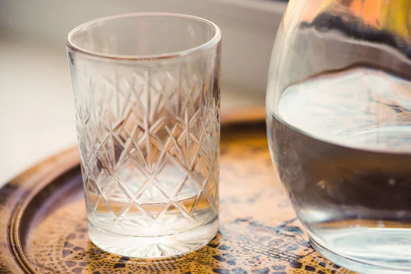 Vidro e jarro de água em uma bandeja de perto — Fotografia de Stock