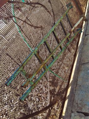 Çit örgü asılı eski demir merdiven.