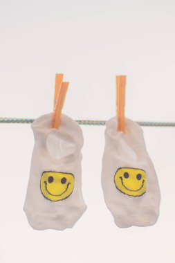 Sarı gülen ifade ile beyaz çorap clothespins ile bir halat asmak. Gökyüzü arka plan.
