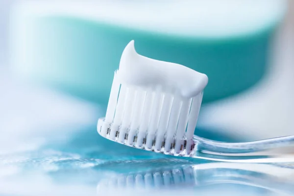 Escova de dentes de plástico com pasta de dentes branca em uma mesa azul — Fotografia de Stock