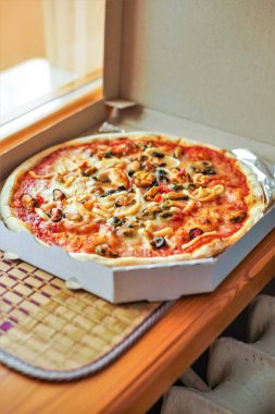 Pencere üzerinde sıcak lezzetli Italyan deniz ürünleri pizza ile açık kutu.
