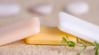 Kahverengi bir havlu üzerinde pastel tonları üç sabun çubukları