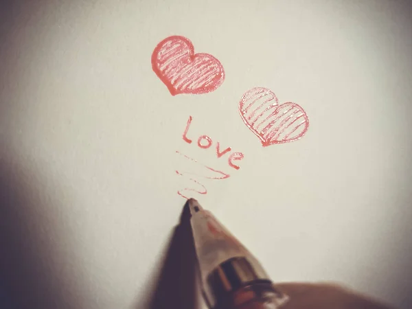 Zwei rote Herzen und ein Stift auf hellem Hintergrund. — Stockfoto