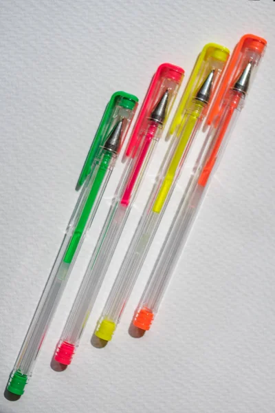Quatro canetas de gel em papel texturizado branco, amarelo, rosa, verde e laranja . — Fotografia de Stock