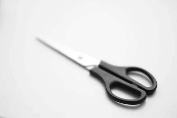 Scissors with a black handle are on the white surface. — Stock Photo, Image