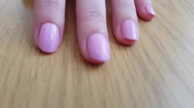 Beyaz deri ve ahşap masada pembe kısa çivi ile kadın el, yakın çekim